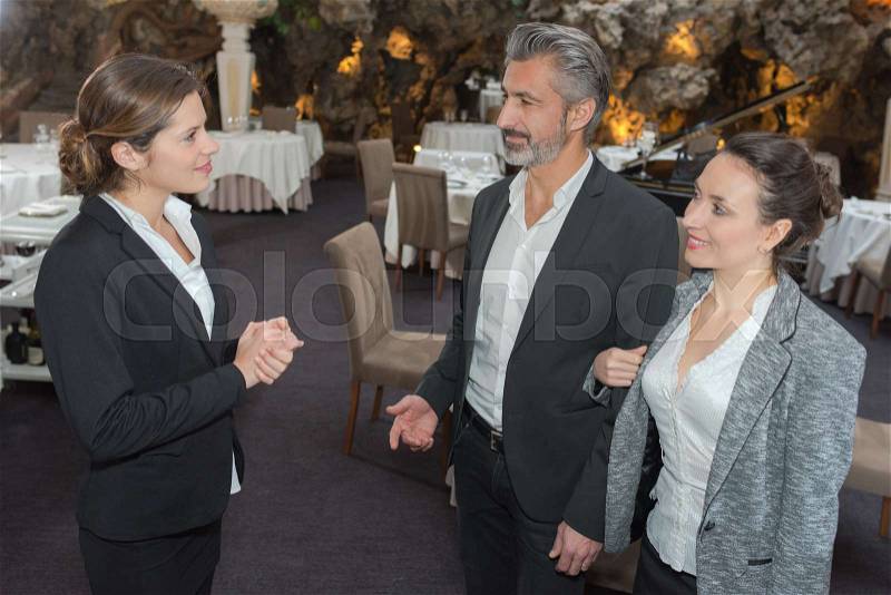 Restaurant manager welcomes a couple in the restaurant, stock photo