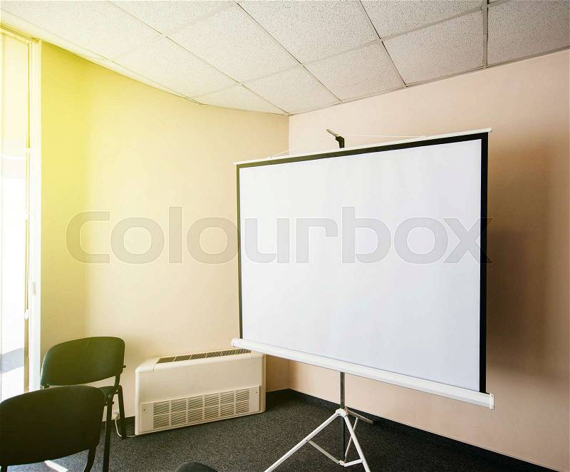 Blank projector canvas in the office seminar meeting room with beautiful sun passing through the window, stock photo
