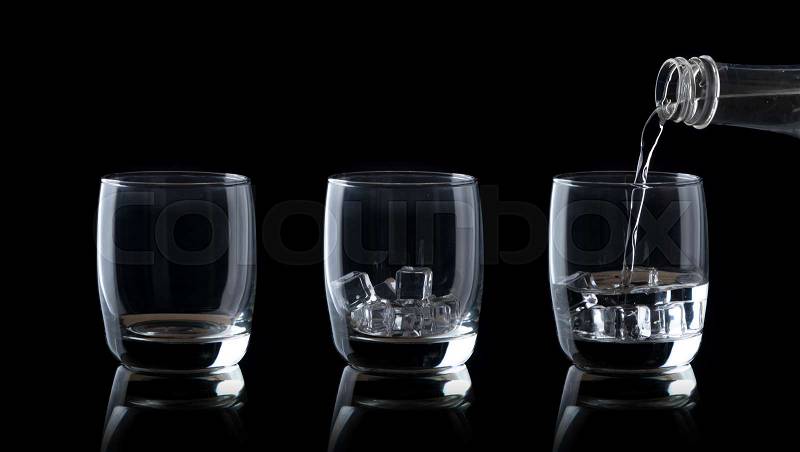 Empty glass and Pouring water drink in to glass with ice on a black background, stock photo