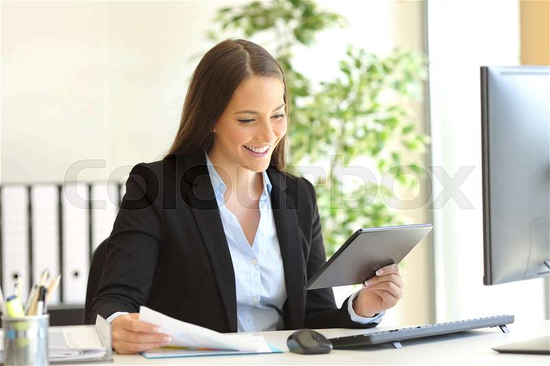 Businesswoman working on line with a tablet checking documents in the office, stock photo