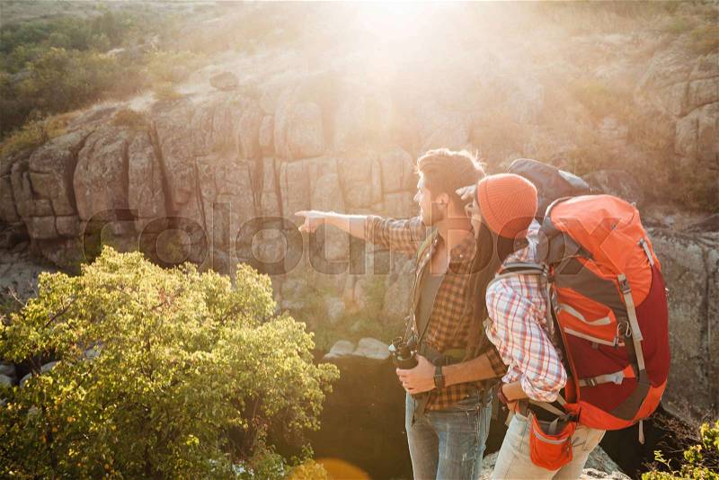Adventure couple stands sideways near the canyon. man shows away, stock photo