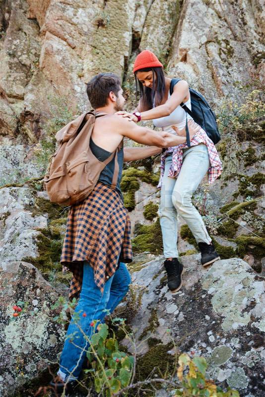 Full length man and woman with backpacks walking on rock, stock photo