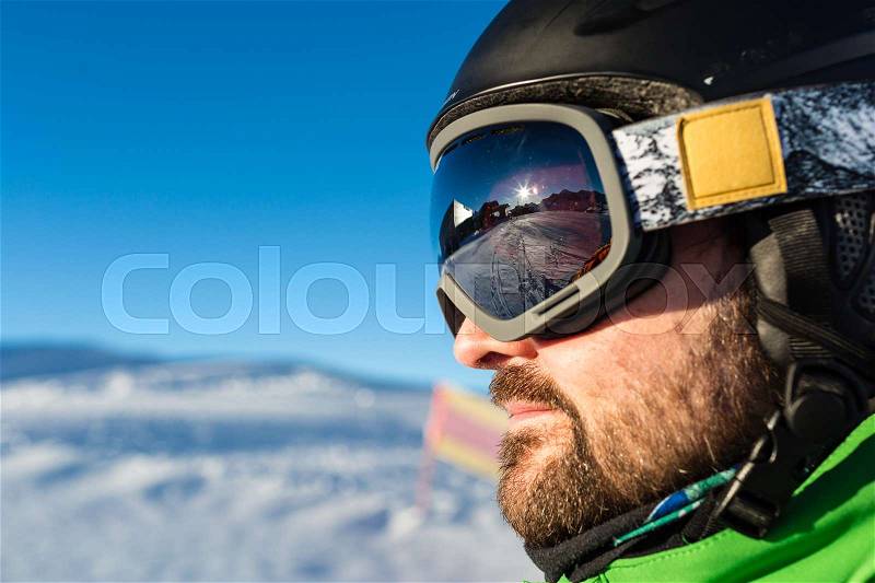 Close-up of male skier with large oversized ski goggles standing on the top of a mountain ready for skiing, stock photo