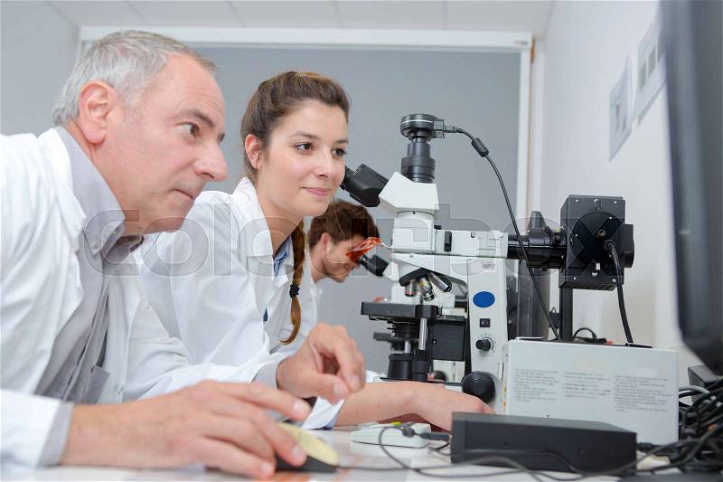 Medical students and teacher working with microscope at the university, stock photo