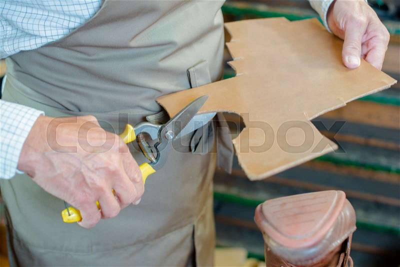 Cobbler cutting out new sole for shoe, stock photo