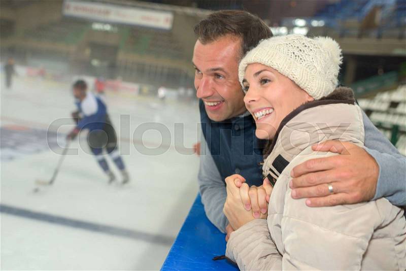 Animated couple watching game of ice hockey, stock photo