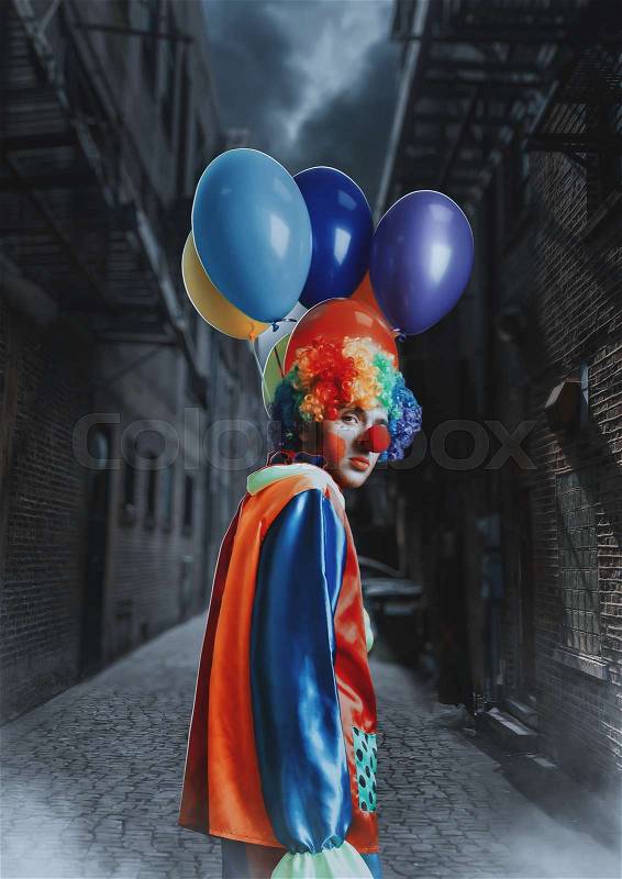 Clown with a bunch of colorful air balloons standing in night alley, stock photo