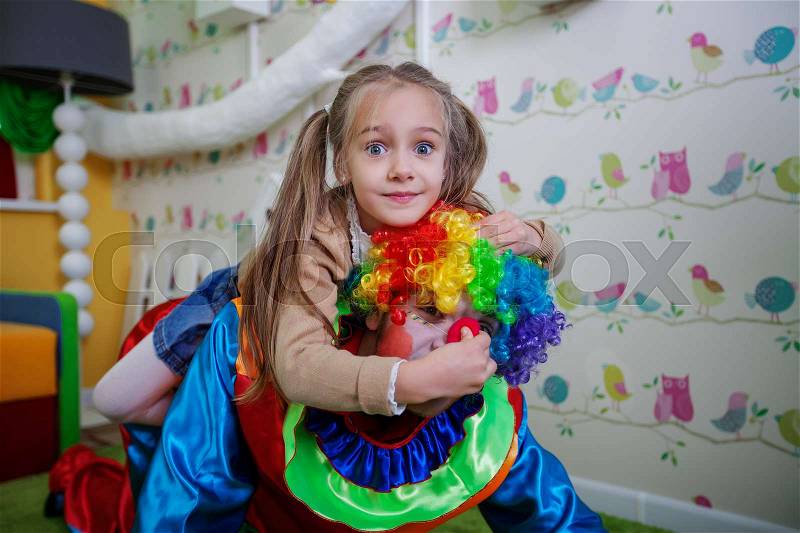 Little girl grabbed a clown nose. Amusement on birthday party. , stock photo