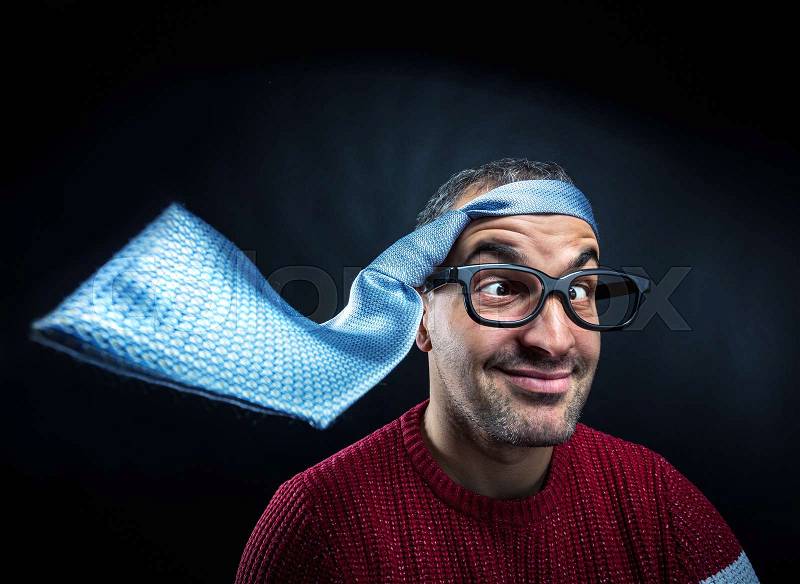 Strabismus man in eyeglasses with tie on his head against black background, stock photo