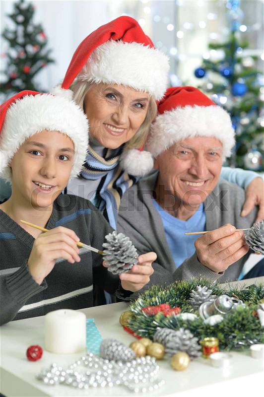Happy grandparents with their teen grandson preparing for Christmas at home, stock photo