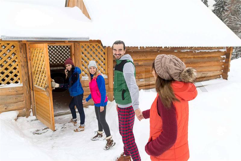 People Group Near Wooden Country House Winter Snow Resort Cottage Friends On Vacation, stock photo