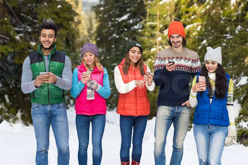 People Group Using Smart Phone Chatting Online Snow Forest Happy Smiling Young Friends Walking Outdoor Winter Pine Woods, stock photo