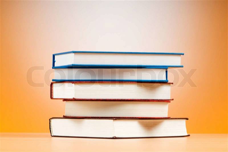 Stack of text books against gradient background, stock photo