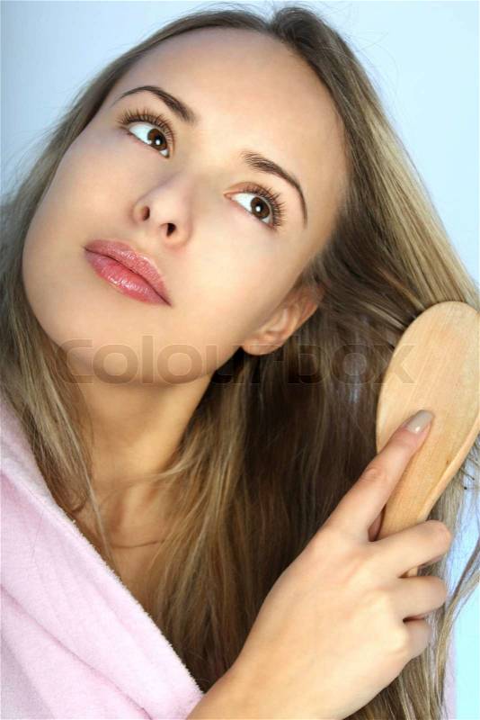 Young woman in bathrobe with comb over blue, stock photo
