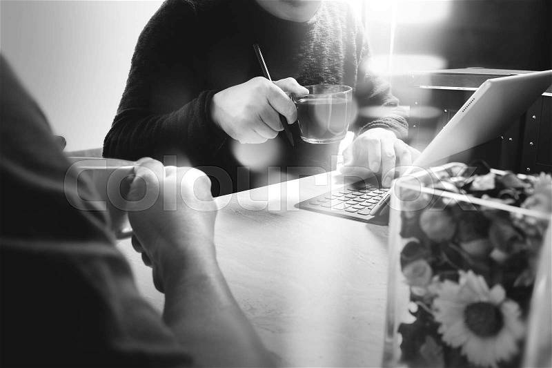 Office coffee break with two designer colleagues sitting chatting over cups of coffee,flower vase,digital tablet docking smart keyboard on marble desk,filters effect film, stock photo