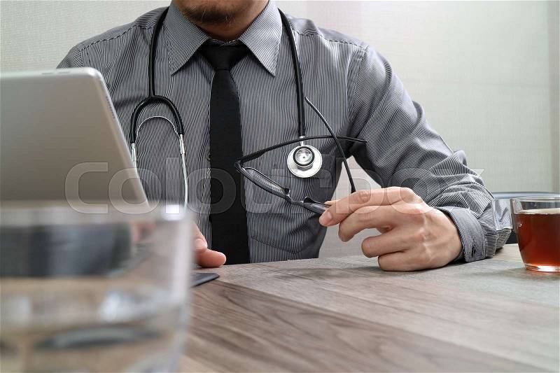 Smart medical doctor hand working with smart phone,digital tablet computer,stethoscope eyeglass,on wood desk, stock photo
