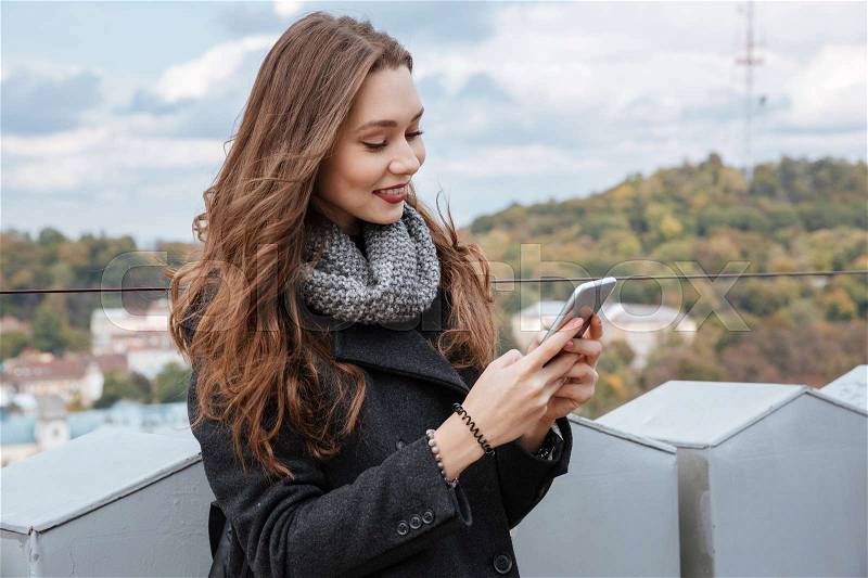 Young model looking at phone. so pretty model. in coat, stock photo