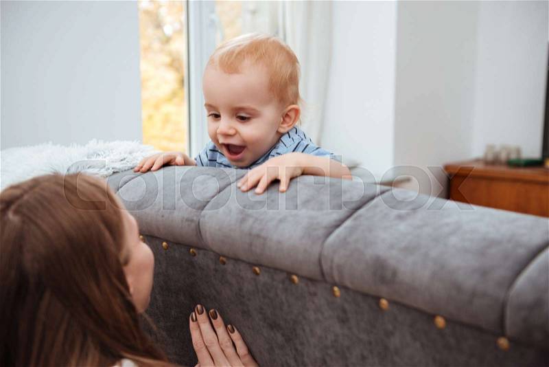 Happy little boy playing with his mother at home, stock photo