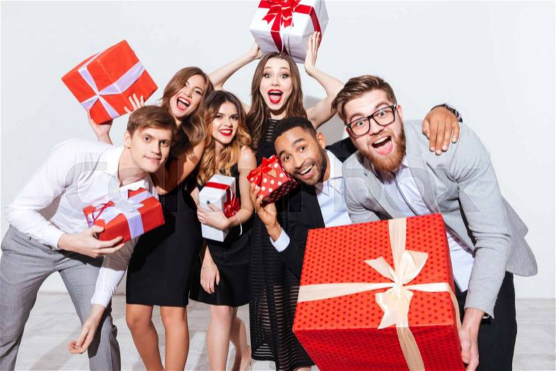 Group of happy funny young people holding gift boxes and having fun over white background, stock photo