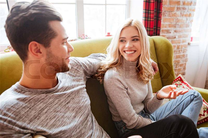 Side view of couple on sofa in home. looking into each other\'s eyes, stock photo