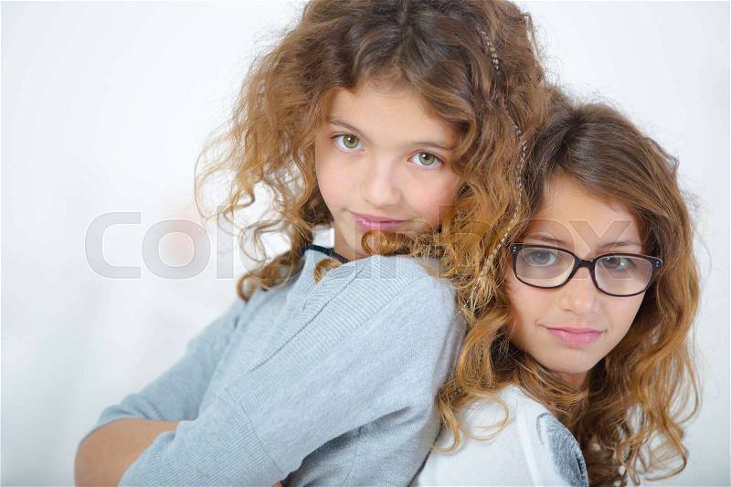 Two young girls stood back to back, stock photo
