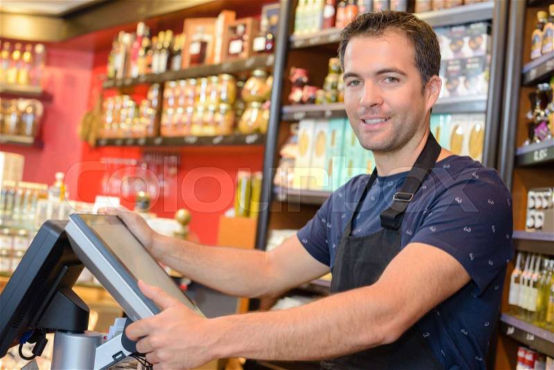 Portrait of clerk stood by electronic cash register, stock photo