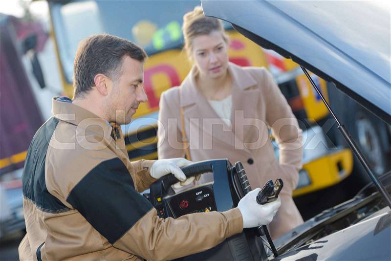 Recovery man using jump starter on car, stock photo