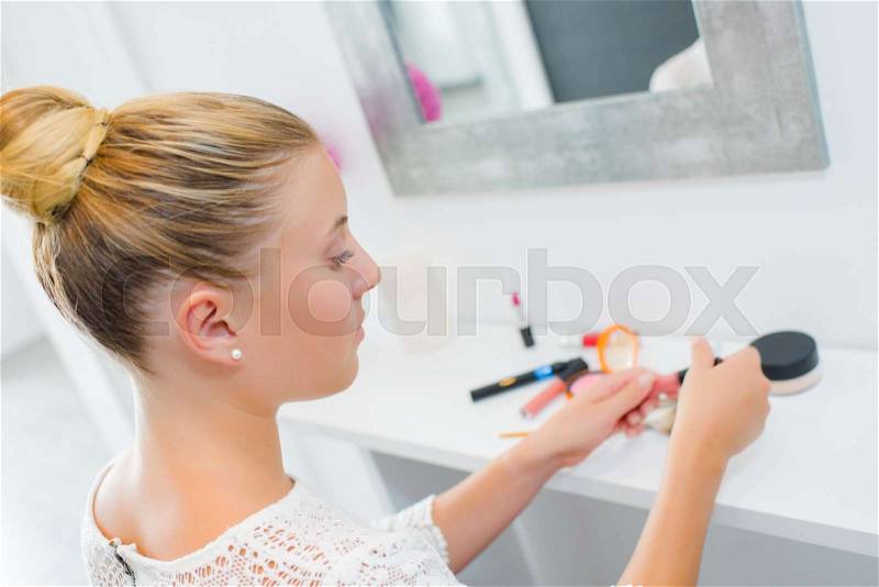 Lady in front of mirror with her cosmetics, stock photo