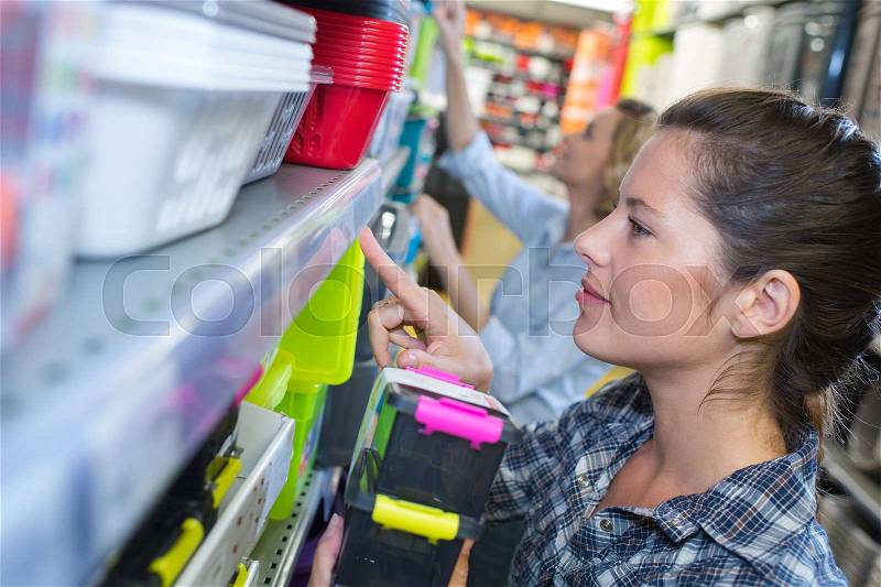 Adult woman in good spirits selecting pails in store, stock photo