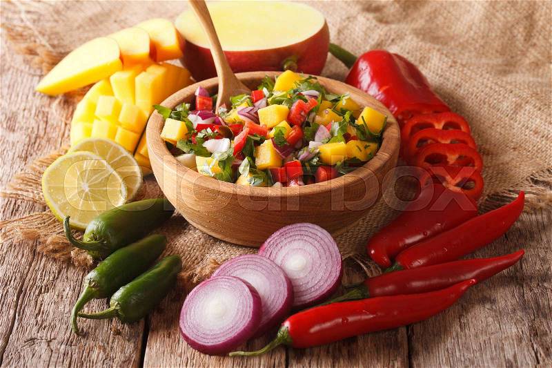 Mexican Food: salsa with mango, cilantro, onions and peppers close up in a bowl and ingredients on the table. horizontal , stock photo
