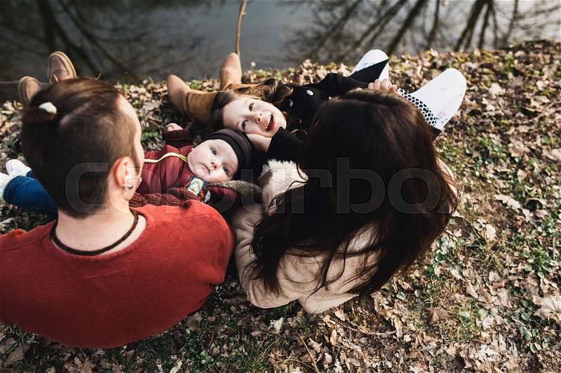 Cheerful and friendly family resting on the river bank in the autumn park, stock photo