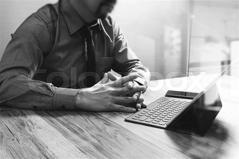 Businessman working with new start up project.using smart phone digital tablet docking smart keyboard and laptop computer on wooden desk,black white, stock photo