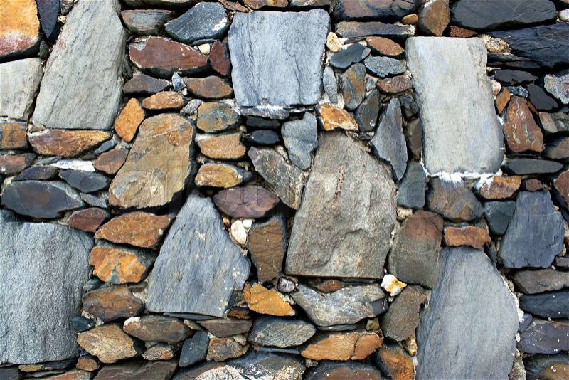 An old stone wall texture with rocks of various shapes and sizes, stock photo