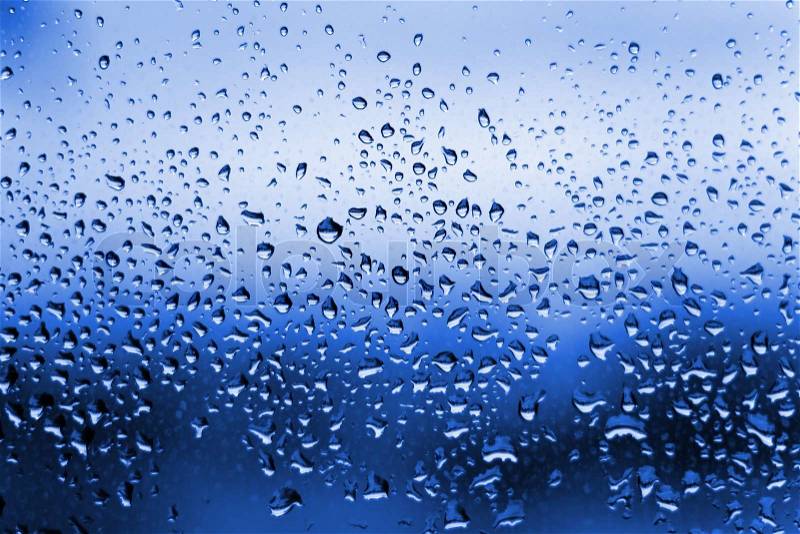 A close up shot of blue water droplets on a glass window pane, stock photo