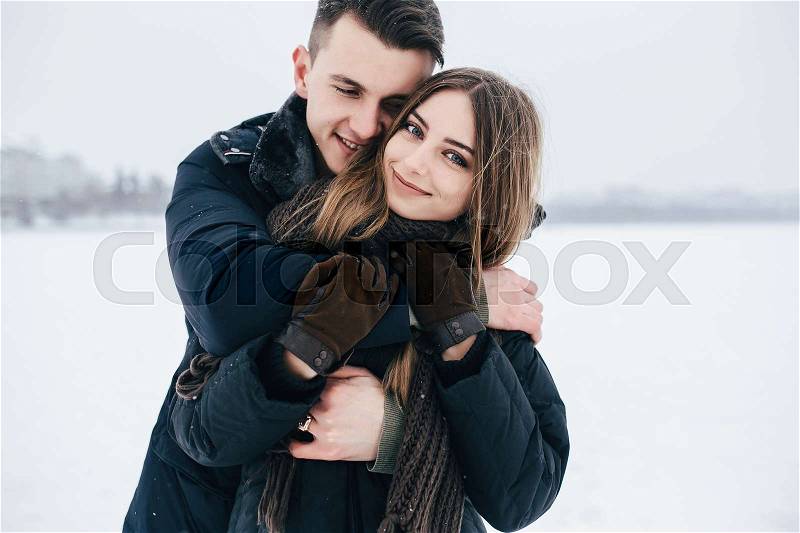 Guy hugging his girlfriend from behind in the park, in winter holidays, stock photo