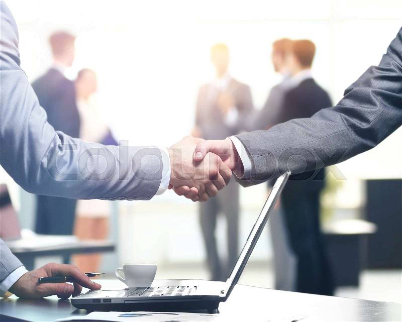 Confident business handshake. Close-up view of a handshake. business office in formal wear and work at a laptop, stock photo