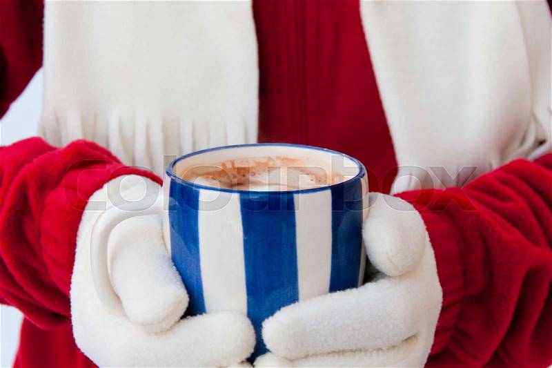Close up midriff photo of a woman in warm gloves holding cup of hot chocolate with marshmallows at winter. selective focus, stock photo
