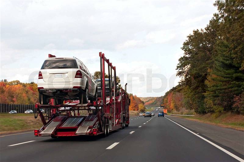 An automotive car carrier truck driving down the highway with a full load of new vehicles, stock photo