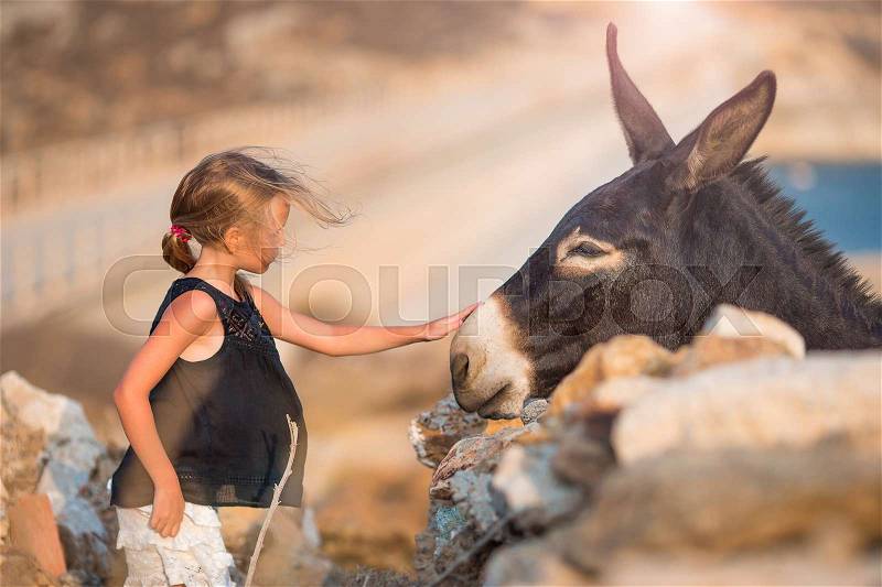 Little girl with donkey on the island of Mykonos, stock photo