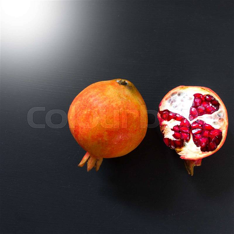 Ripe pomegranate fruit on black background, stock photo