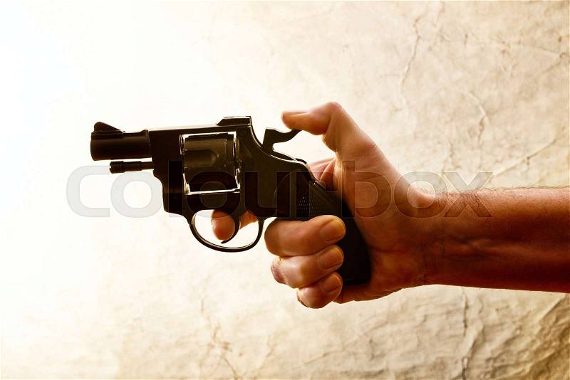 Silhouette of a mans hand with a handgun in brown, stock photo