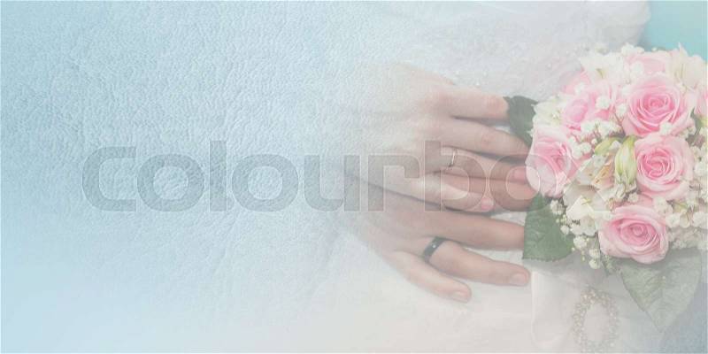 Bride and groom hands with wedding rings and bouquet of roses on the blue background, stock photo