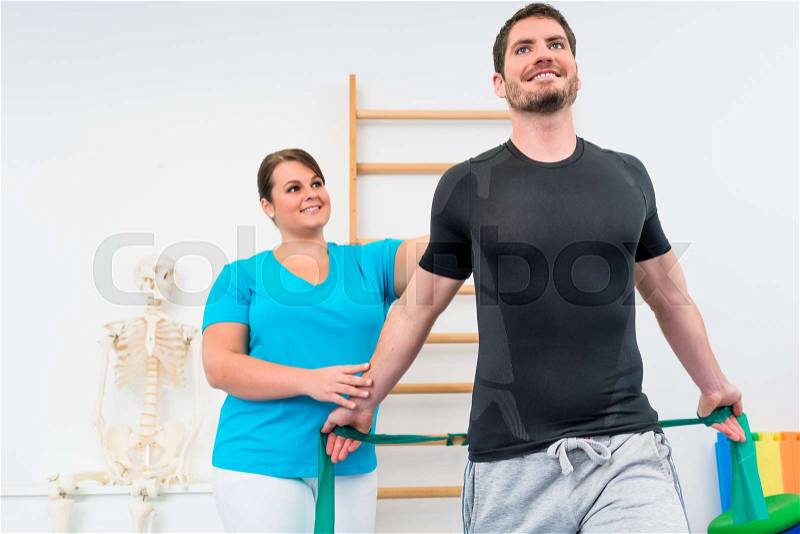 Young man working out with physiotherapist and resistance band, stock photo