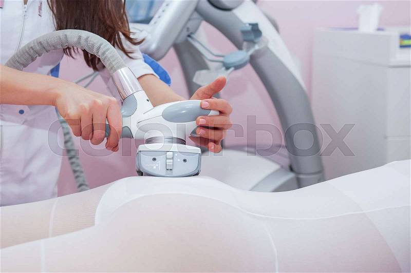 Parts of female body in special white suit having anti cellulite massage with spa apparatus, stock photo
