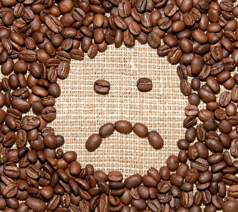 Coffee beans sad smile on burlap background, stock photo