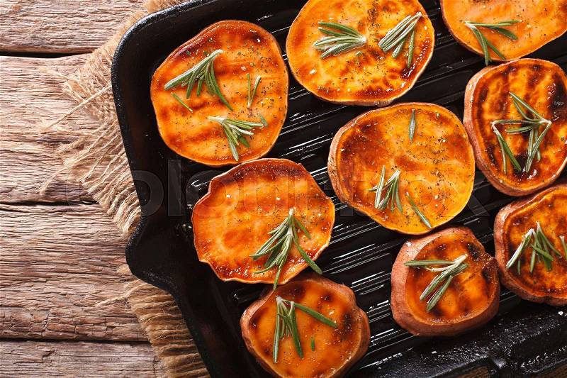 Roasted sweet potatoes with rosemary on the grill pan on the table close-up. horizontal view from above , stock photo