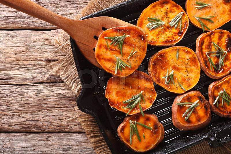 Simple Food: Grilled sweet potatoes with rosemary on the grill pan on the table close-up. horizontal view from above , stock photo