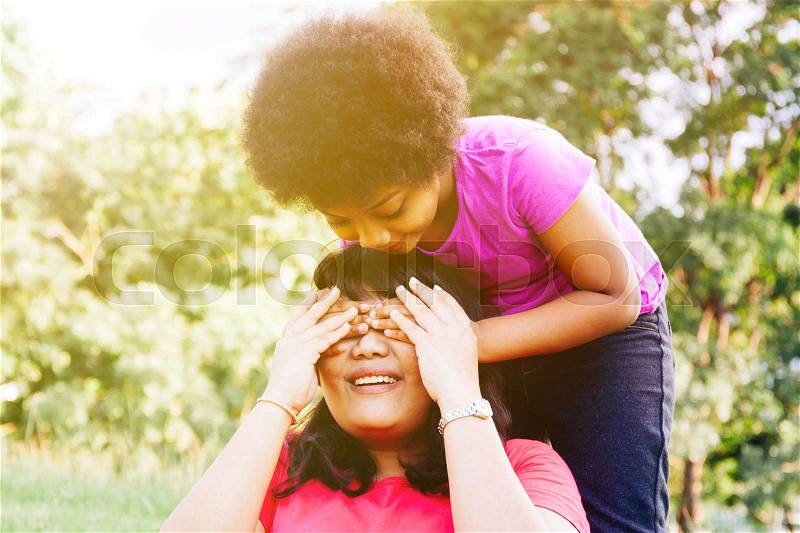 Kid covering mother\'s eyes in the green park with copy space - Daughter and mother relationship, stock photo