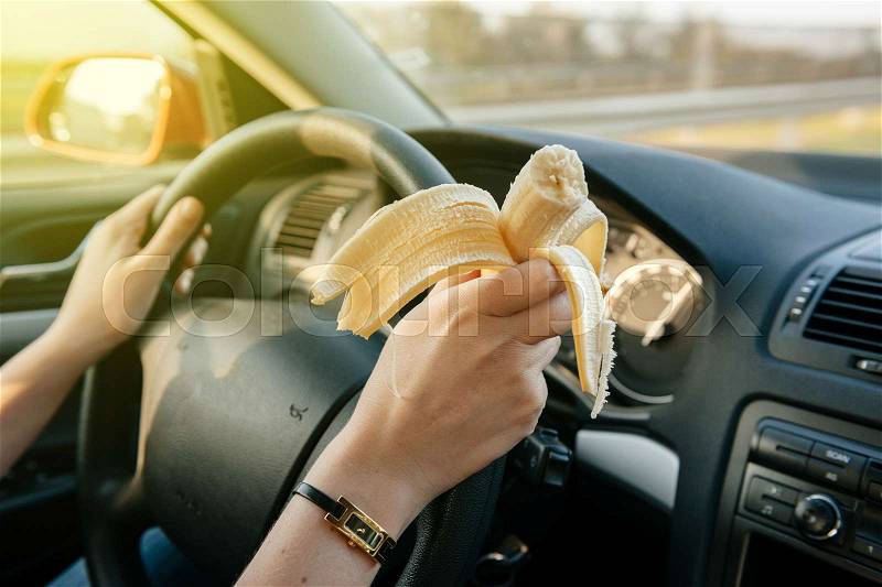Woman eating a banana while driwing car on highway with 120 km/h, stock photo