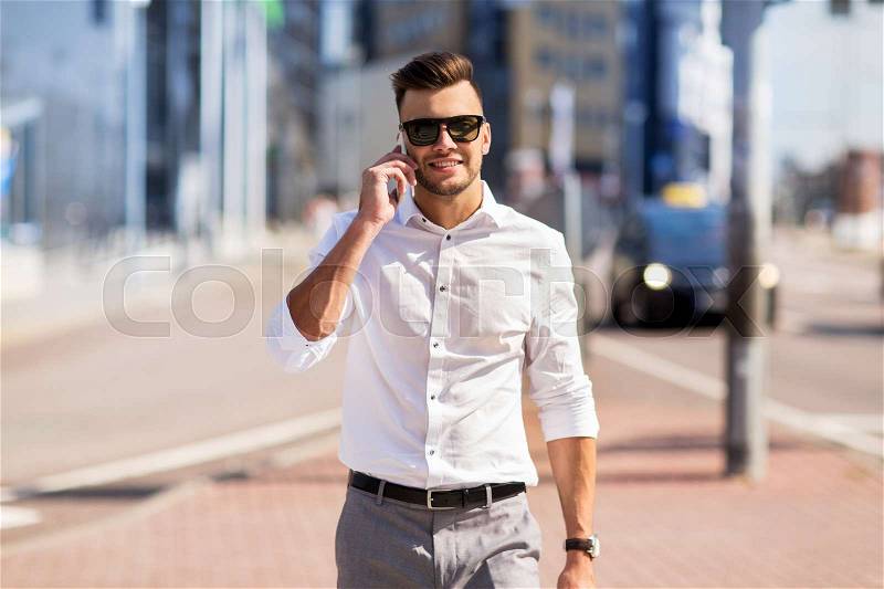 Technology, communication and people concept - happy man with smartphone calling on city street, stock photo